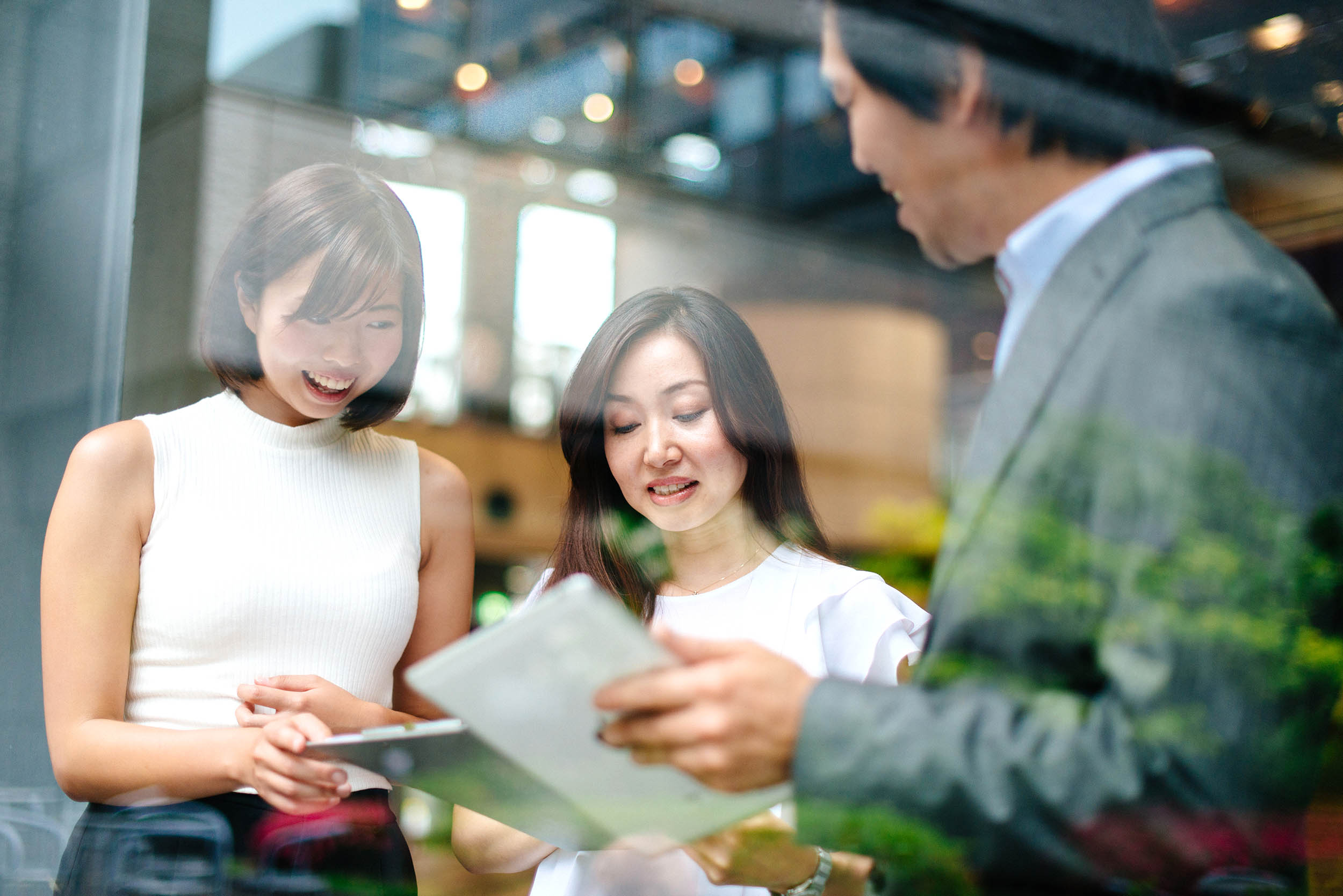 hree Japanese business people in modern office building chatting and discussing about business opportunities and perspectives